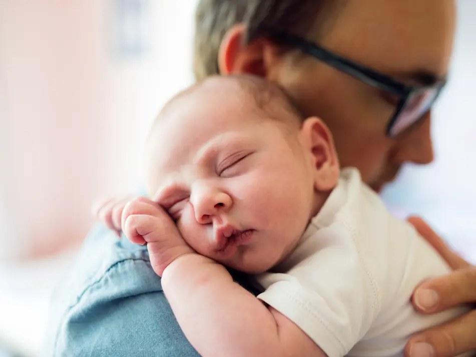 Father holding newborn baby demonstrating responsive parenting advice.