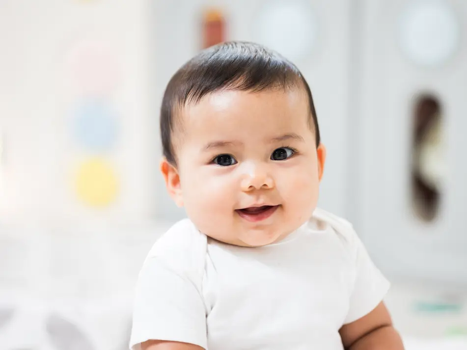 Happy baby smiling, supporting parenting tips for baby care.