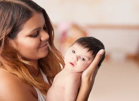 Mum holding newborn during daily routine, supporting newborn care and daily rhythm advice