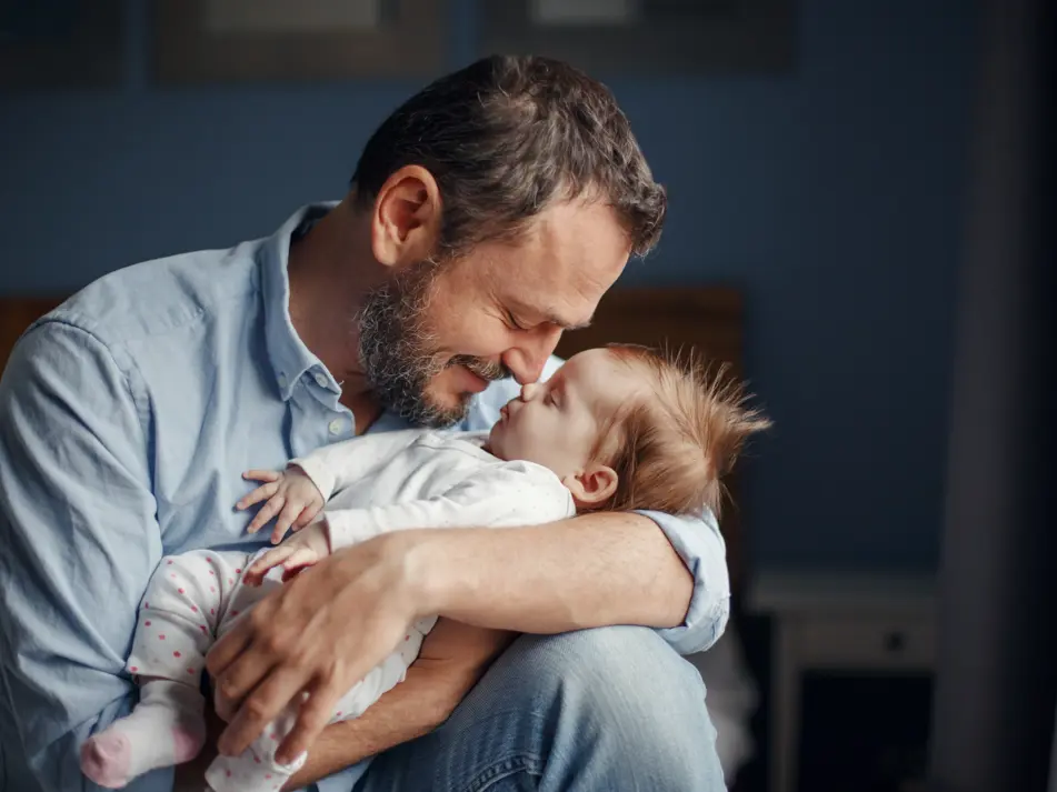 Baby sleeping in dad's arms, supporting baby sleep tips and settling routines for parents
